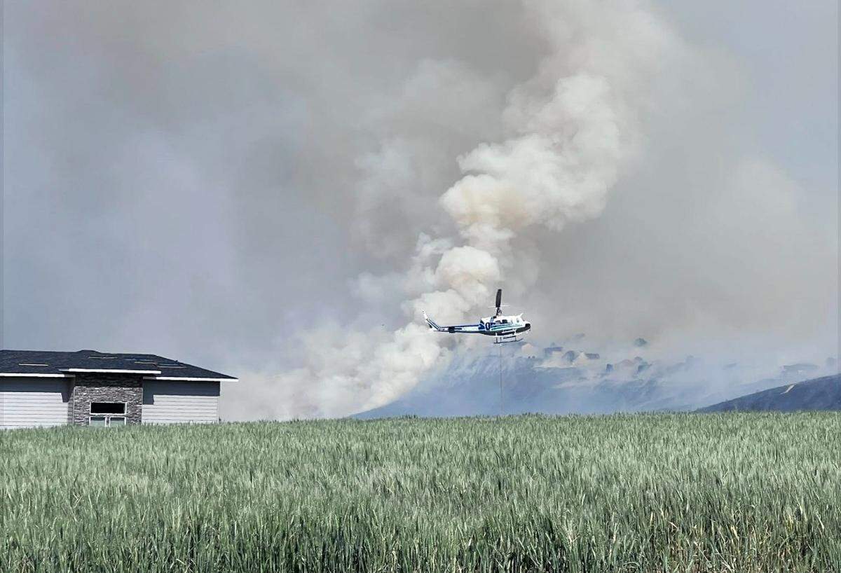 A helicopter works to protect homes from the Country Meadows Fire in Badger Canyon on Saturday afternoon.