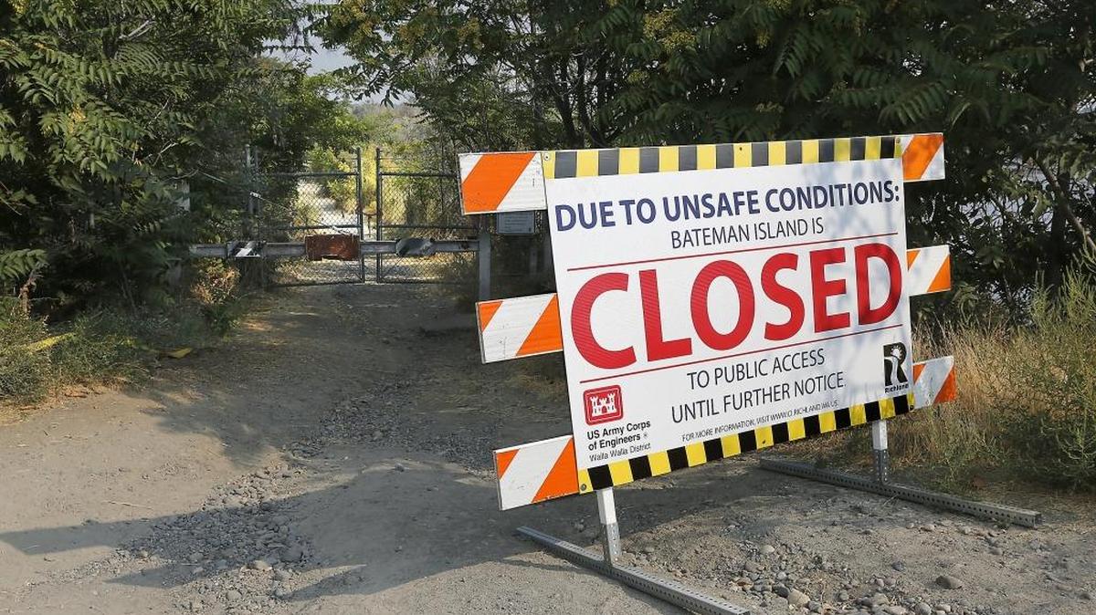 A brightly colored sign posted on a barricade posted near the causeway of Bateman Island reminds users the popular site is still closed following a wildfire earlier in the year.