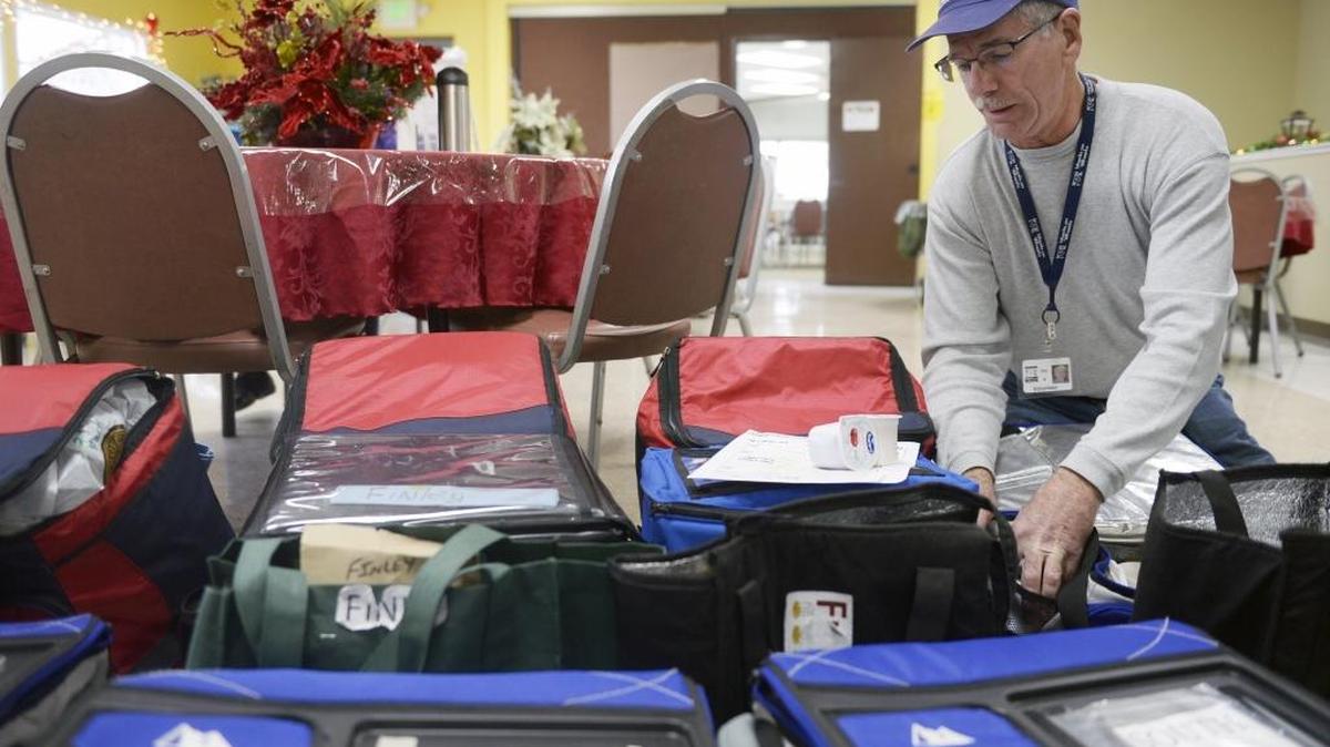 A volunteer driver checks his delivery bags in this file photo.