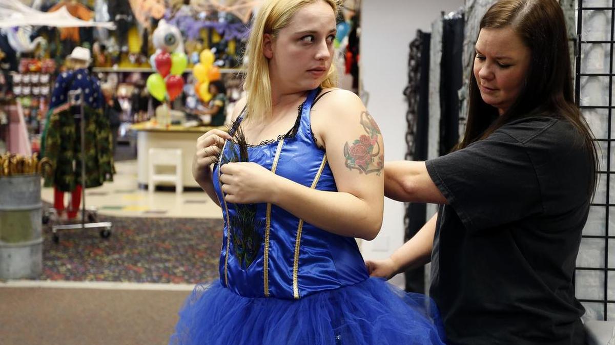 Isabella Wagoner, left, of Kennewick, gets some help getting into a peacock costume Friday from Let’s Party Manager Deanna Madrigal at the store on Edison Street in Kennewick. For more Halloween and fall activities go to bit.ly/halloweenhaps1