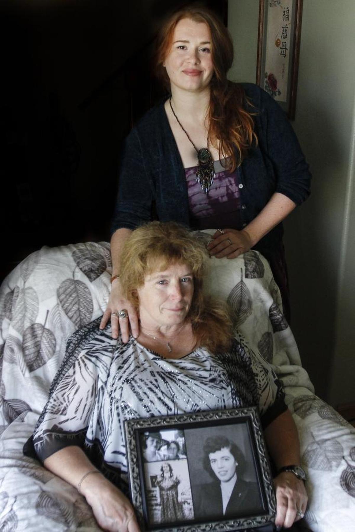 Erika Young, top, and her mother, Jan Seely, pose for a photo in Seely’s home in Kennewick. Seely is holding a photo of her birth mother, Ida Murphy.