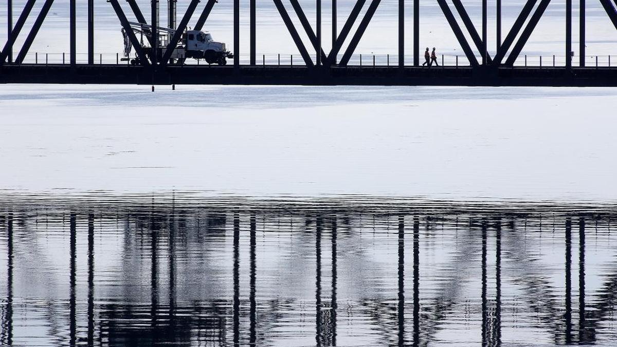 
A pair of railroad workers walk Wednesday across the Burlington Northern Santa Fe Railway lift bridge over the Columbia River between Kennewick and Pasco while apparently performing maintenance on the structure.
