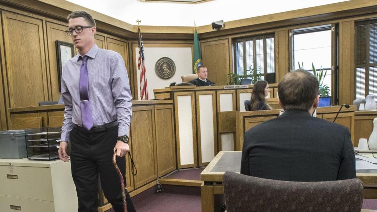 Drew Schreiber, who was brutally beaten with a baseball bat by three men in October in the parking lot of his apartment complex, walks past defendant John Mellgren, sitting, after testifying April 13 in Spokane. Drew was a student at EWU and a member of the track team.