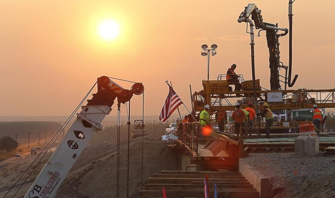 The sun rises behind the new overpass being constructed on Highway 124 about five miles east of Burbank early Friday morning as construction workers pour the concrete deck. The deck pour for the $11 million project was delayed a couple weeks recently because of the high daily and overnight temperatures.