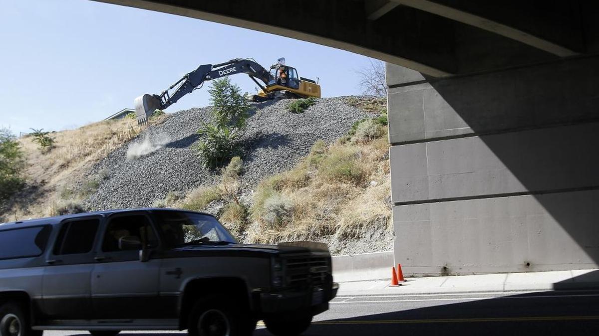An excavator operated by Kennewick city employee Josh Soggie drops a load of rock Wednesday onto a hillside at the dead end of North Underwood Street, near the Highway 395 overpass on West Canal Drive in Kennewick. Heavy rainstorms in May washed part of the dirt face of the hill onto Canal Drive. The project is to repair the storm damage and as well as prevent erosion from future storm runoff.