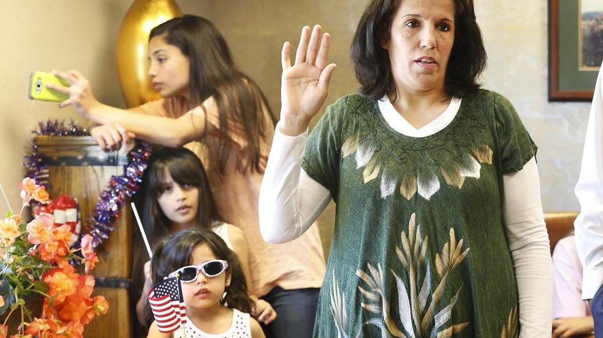 Adela Hamza, 48, of Richland, takes her citizenship oath Wednesday during a ceremony at her attorney’s office in Pasco. Daughters Sarah, Farah and Zahraa, from the bottom, attended the ceremony conducted by a U.S. Citizenship and Immigration Services official. Hazma and her husband, Mushtaq Jihad, who have been featured in the Herald several times, came to the Tri-Cities in 2008 as refugees from Iraq.