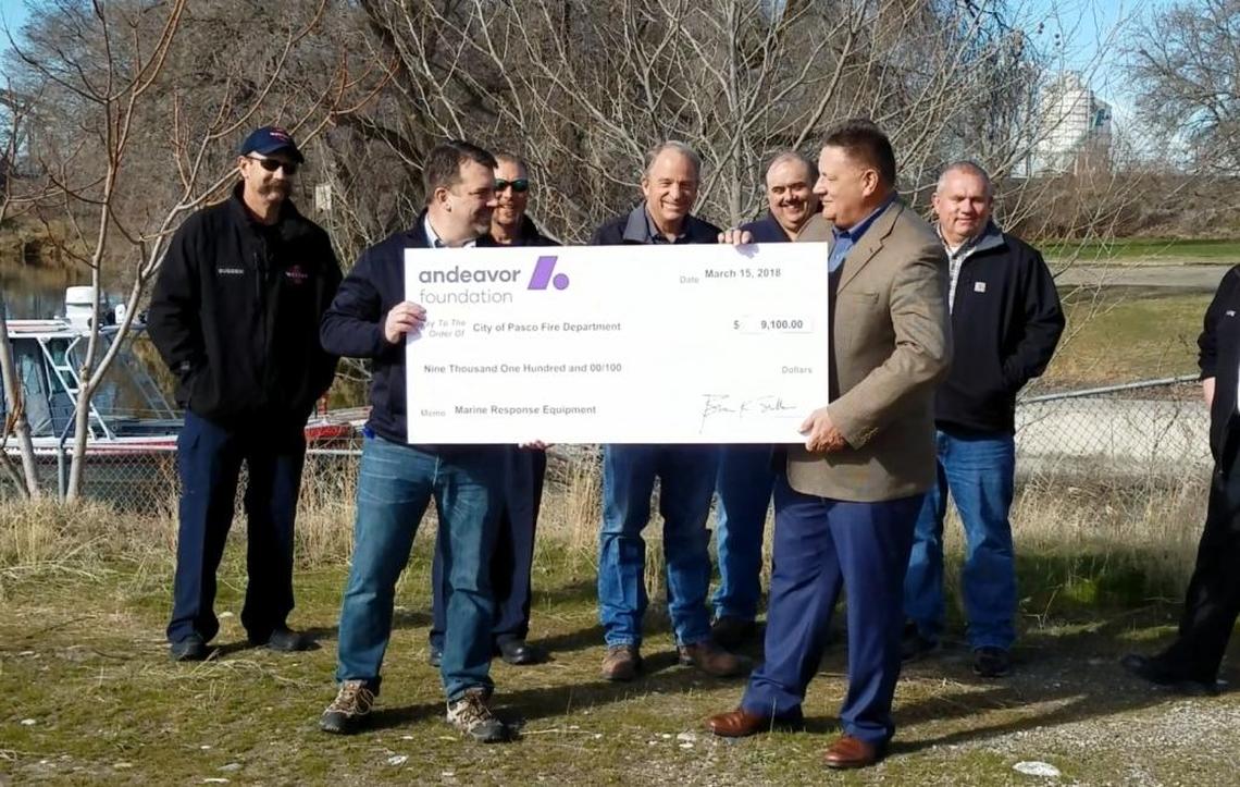 Representatives from Andeavor hand over a ceremonial check to City Manager Dave Zabell.