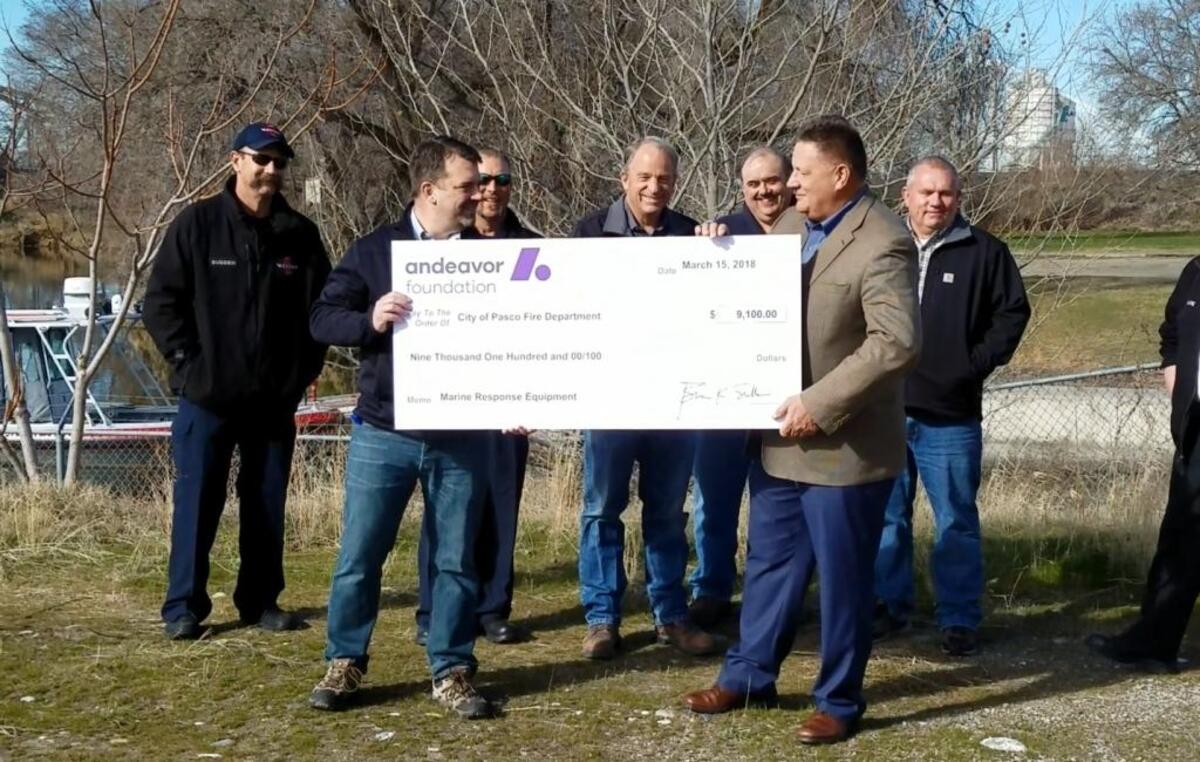 Representatives from Andeavor hand over a ceremonial check to City Manager Dave Zabell.