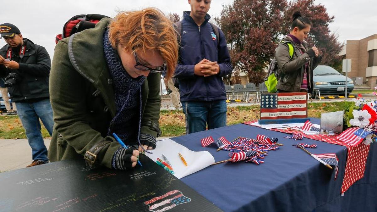 Maya Yoakum, left, writes a message on a board dedicated to veterans after Columbia Basin College organized a Veterans Day ceremony Wednesday at the veterans monument on the Pasco campus.