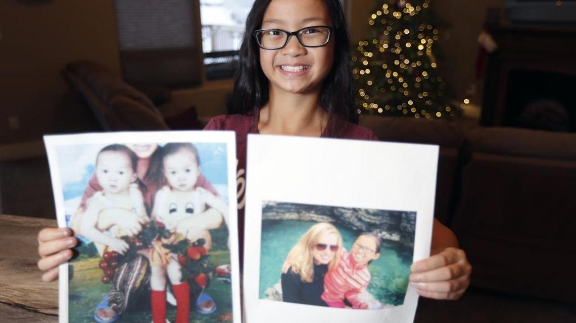 Richland fifth-grader Gracie Rainsberry, 10, holds a photo believed to be of her with her twin sister Audrey, from whom she was separated in China when they were 15 months old. The other photo is of Audrey with her adoptive mother in Wisconsin.