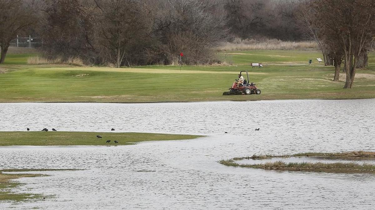 A grounds crew worker at the West Richland Golf Course mows Monday morning up to the edge of Yakima River flood waters that partially covered the course over the weekend. The course is remains open with nine holes of play available in a modified order, according to owner Michelle Marcum. The level of the Yakima River is forecast to continue dropping in the Tri-Cities through the rest of the week.