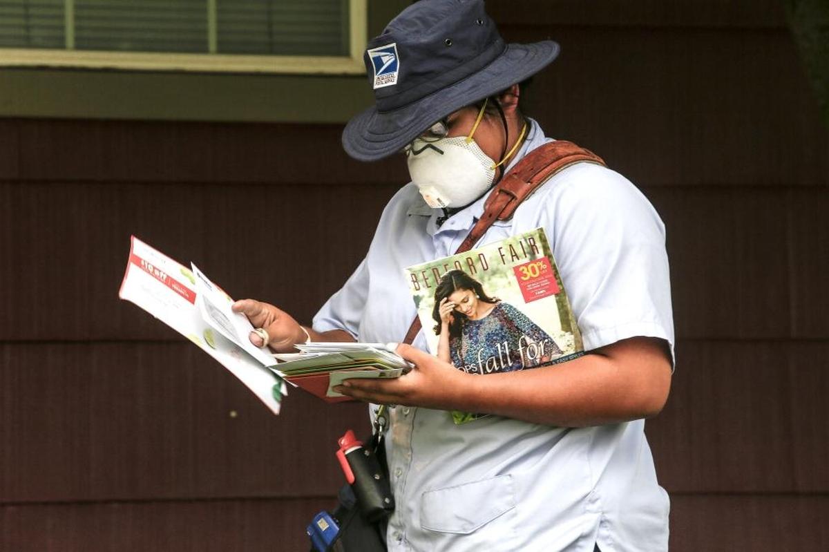 Hermelinda Magaña of the United States Postal Service delivers mail while wearing a respiratory mask in Kennewick on Tuesday. Magaña said the post office gave all its employees face mask to keep them safe from breathing in smoke.