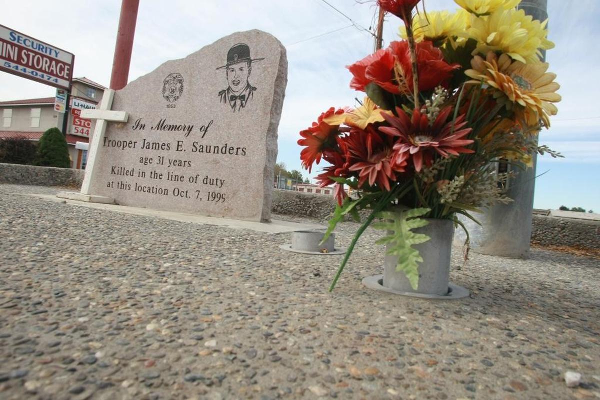 An autumn bouquet of flowers and a white cross in 2009 adorn the permanent memorial marker on Road 28, just south of Lewis Street in Pasco, where Trooper James Saunders was killed 10 years ago on Oct. 7.