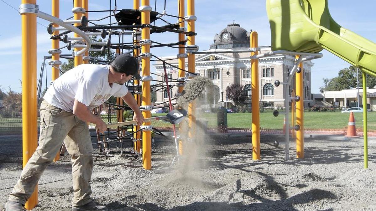 
Josh Grau, an employee of R&R Construction of Buckley, spreads gravel around a newly installed playground structure Wednesday morning at Volunteer Park in Pasco. Grau and two other workers also recently installed a set of swings near the new playground equipment featuring climbing sections and a slide. The workers weren’t sure when the new toys will be open for use.
