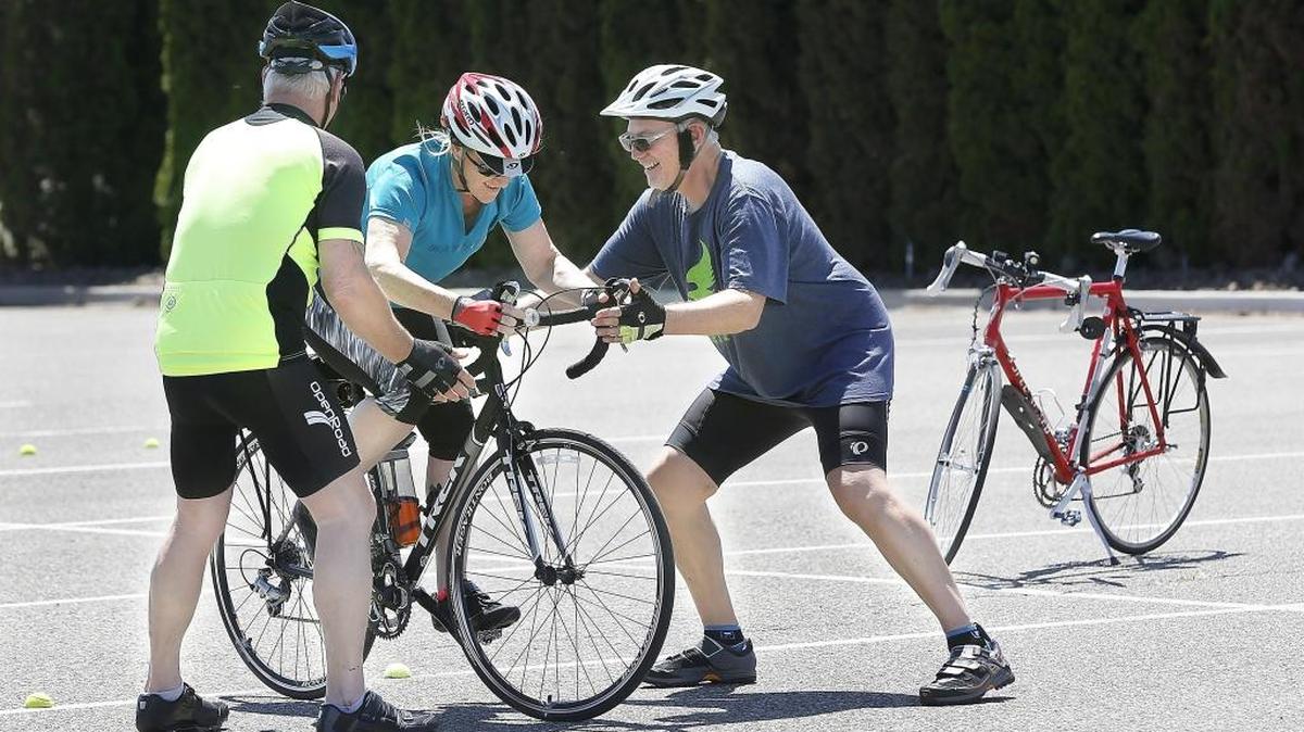 West Richland bicyclist Serena Grandstaff brakes hard as Kim Green, left, and instructor Mike Watkins act as spotters to keep her from tipping over during the emergency stop crash avoidance training drill Monday at Badger Mountain Community Park in South Richland. Watkins, of Roundabout Cycling mobile bike service, is a certified bicycle safety instructor with the League of of American Bicyclists.