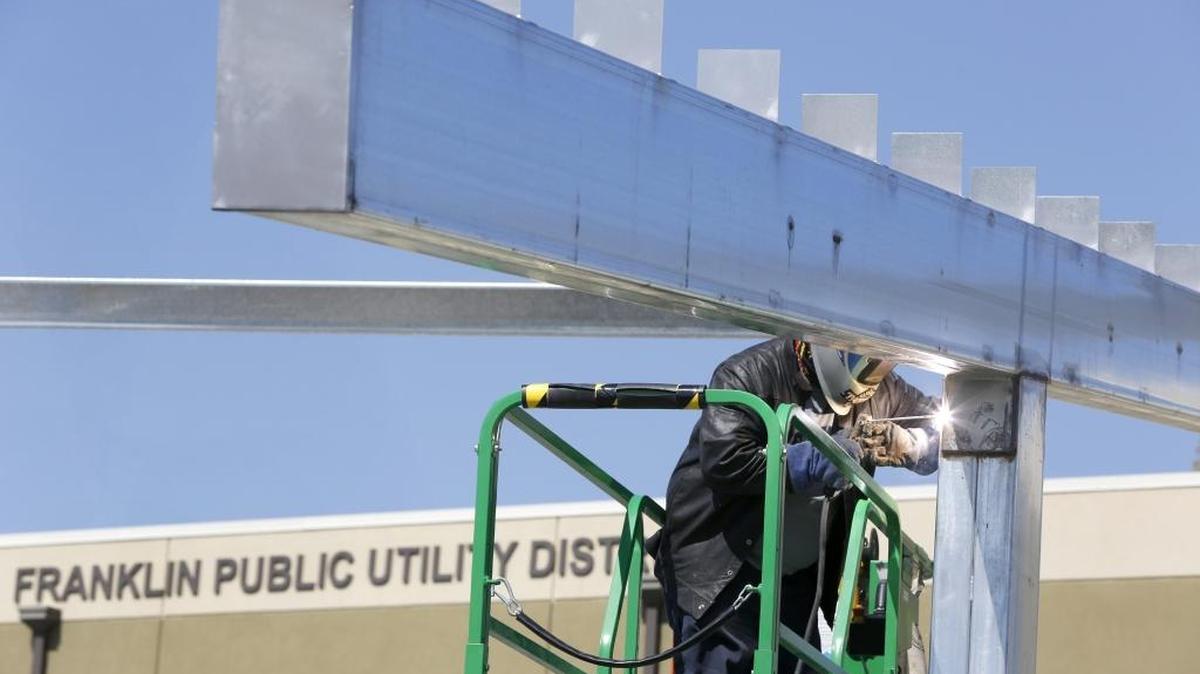 Ivan Morales, an employee of Baja Construction, welds support plates Monday to a metal solar panel structure being built in the Franklin PUD parking lot in Pasco. The PUD is modeling the array off a similar carport design used at Walla Walla Community College. It will shade 26 parking spaces – half publicly accessible, half within the PUD headquarters fenced compound – and generate 60 to 65 kilowatts of energy with 225 solar panels. A-R Solar of Seattle is the general contractor for the project which is expected to be completed by the end of the month.