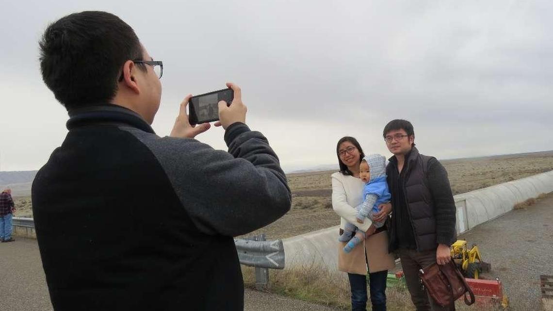 Visitors touring Hanford LIGO snap a photo in front of one of the observatory’s vacuum tubes that stretches across the shrub steppe landscape.