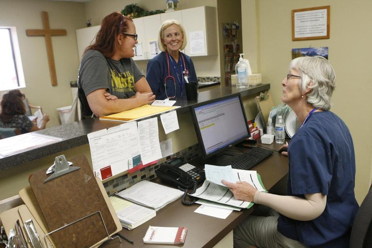 A receptionist at Grace Clinic in Kennewick helps arrange a follow-up visit for a patient in this 2013 photo.
