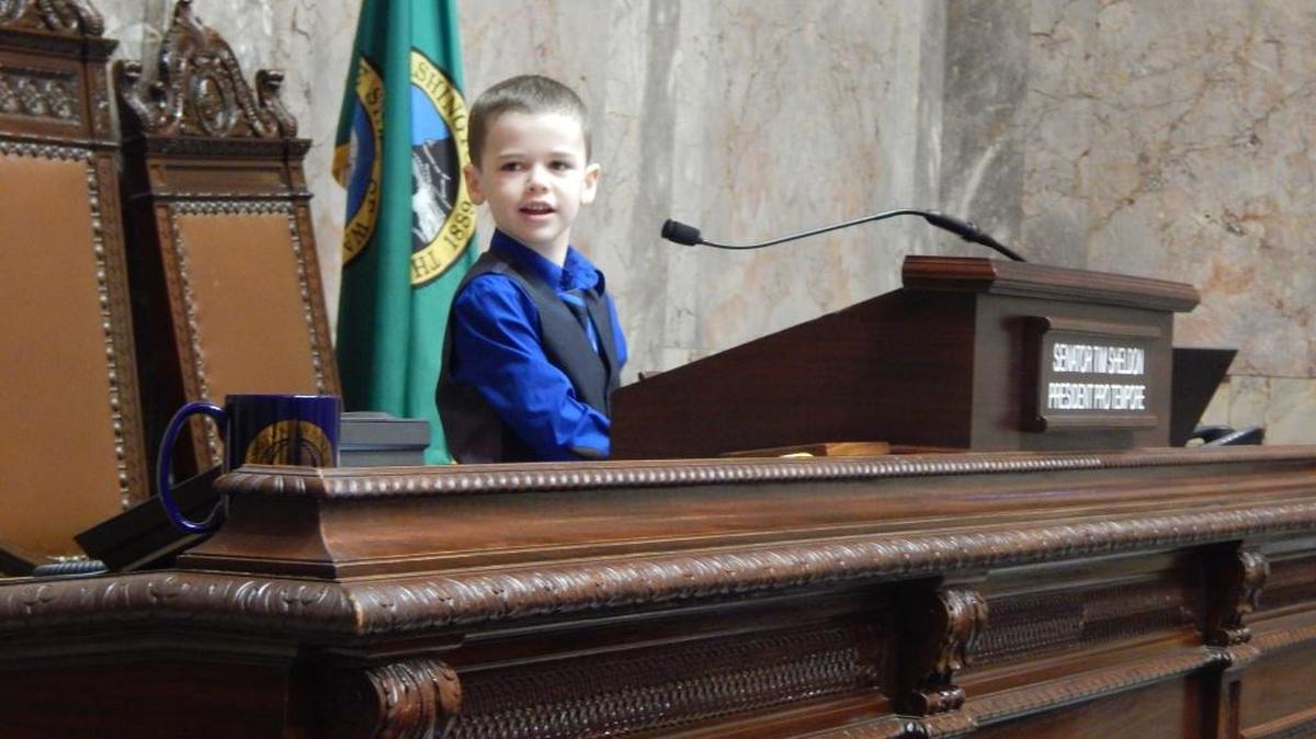 Luke Lynch, 7, of Moses Lake, plays Friday at the podium of the state Senate after a memorial resolution was read honoring his father, Kyle Lynch, who died of cancer in November. Kyle Lynch was an aide for two 13th District senators from 2003-16.