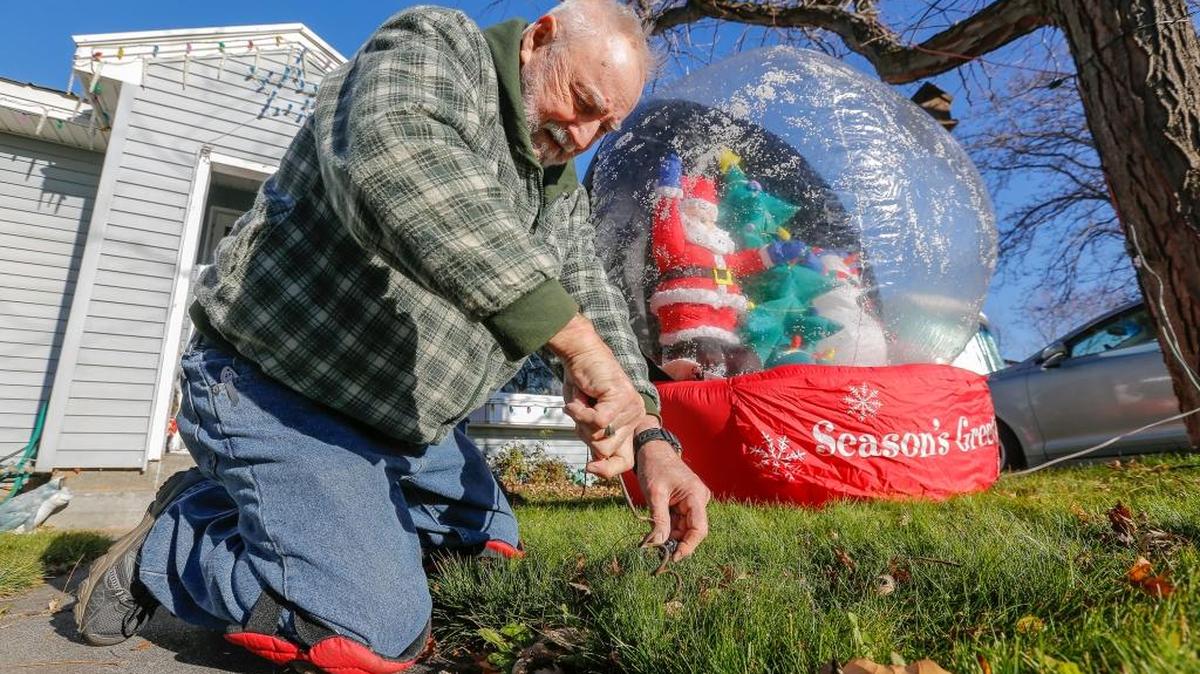 Jim Baker screws a stake into the grass Tuesday to tie down his Christmas decorations on his lawn in Kennewick. Baker has decorated the outside of his house for every major holiday for the past 20 years.