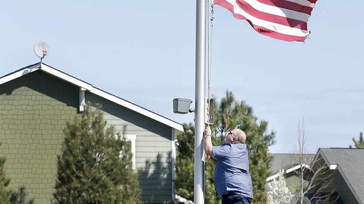 Scott Pierce, a maintenance employee with Ben Franklin Transit, works from an aluminum step ladder Wednesday to lower the U.S. Flag at the organization's 22nd Avenue transfer station in Pasco. Pierce said flags at the agency's facilities were being lowered to half staff to follow a Presidential proclamation for a four-day remembrance of those killed and injured in the terrorist bombings in Brussels, Belgium.
