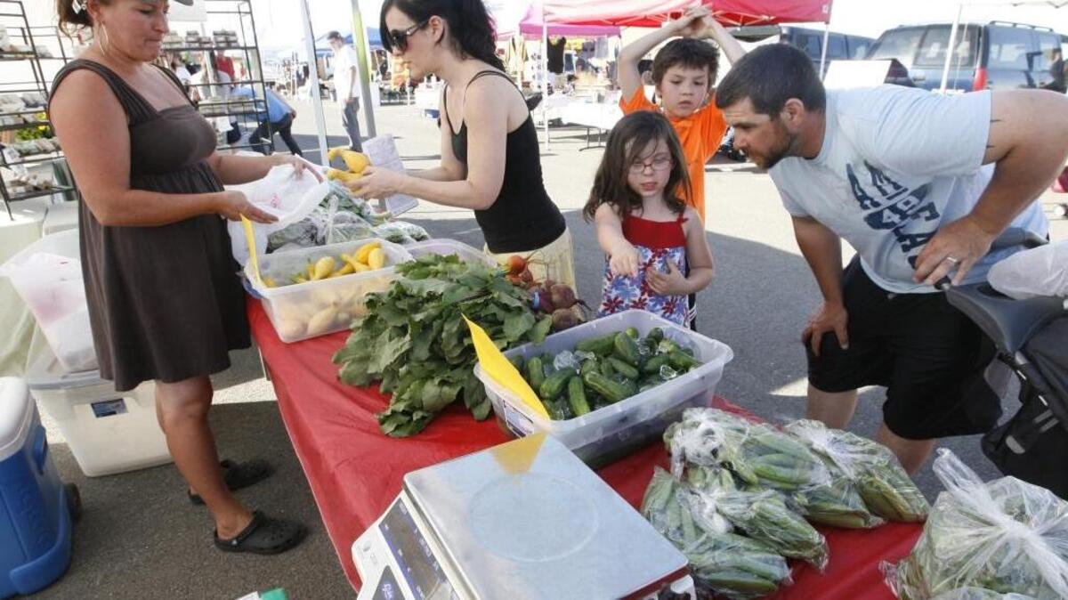 The Pevey family of Kennewick checks out Debbie Crafton’s vegetables at the Southridge Farmers Market in 2013.
