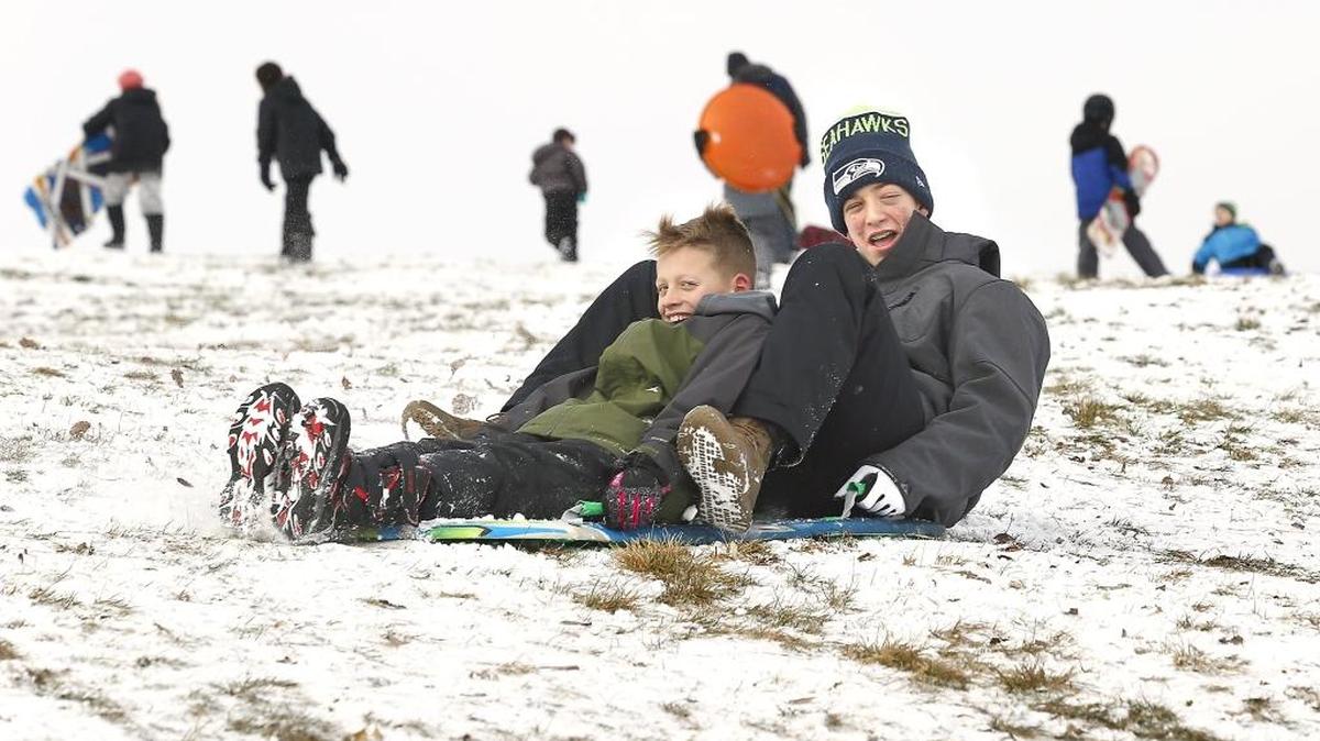 Brothers Luke, 10, and Landen Schroeder, 13, share a sled ride Tuesday morning down the hill at Carmichael Middle School in Richland. The popular sledding site was covered with snow and sledders during winter break for students around the Mid-Columbia.