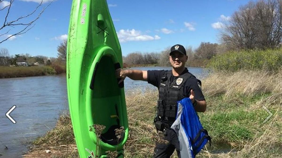 A Richland police officer standing on the shore of Yakima River holds one of the kayaks. A woman fell into the river near Richland on Sunday afternoon after the kayak she was in capsized.