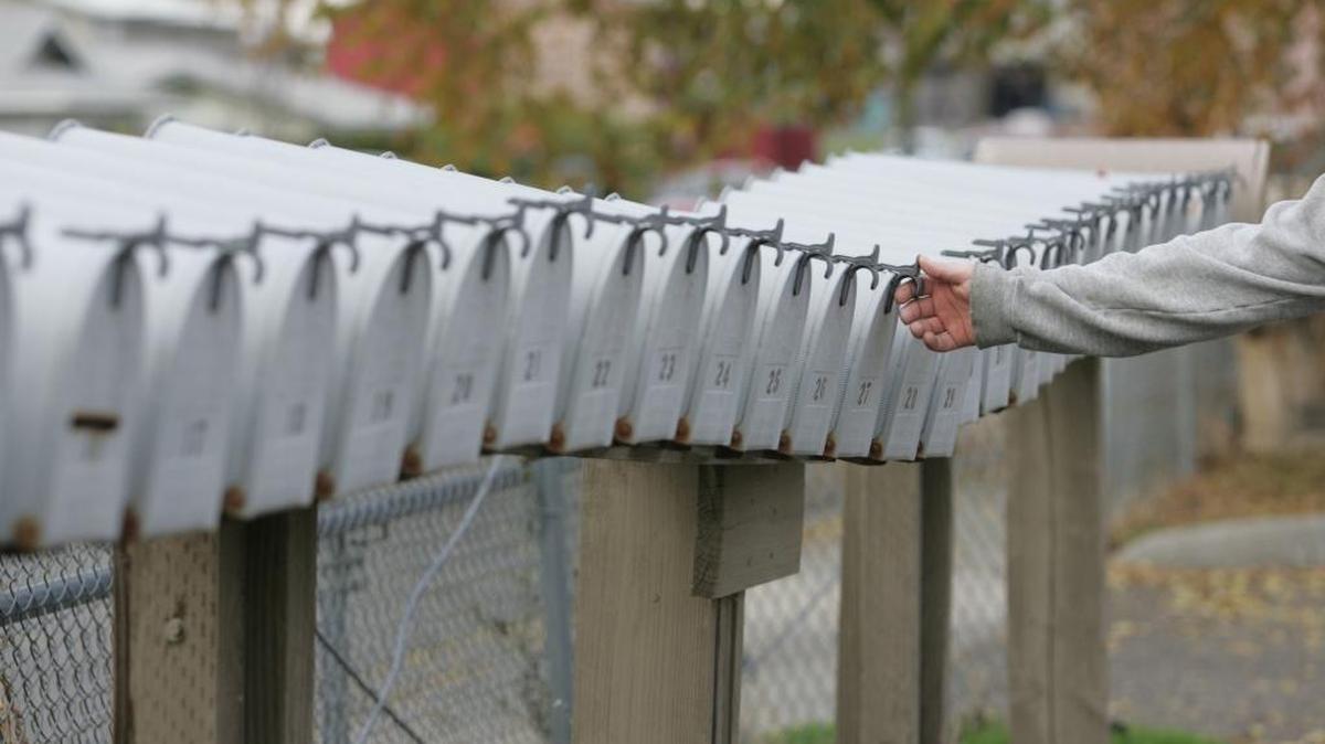 A Pasco resident checks his mail among a long line of boxes in front of his apartment building in this file photo.