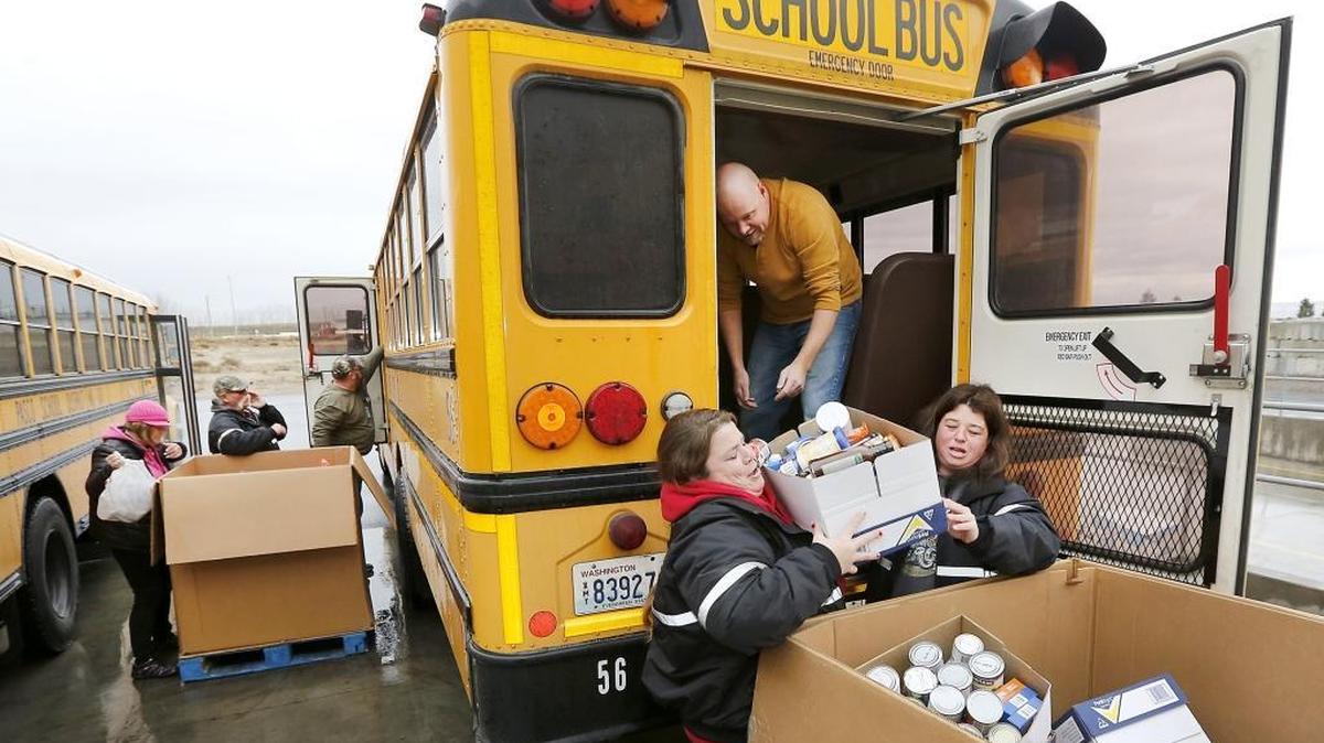 Pasco bus drivers Emily Wantz, left, and Jaime Cornelius work Monday to unload a box from co-worker Isaiah McCollum of donated canned goods at Second Harvest in Pasco. About a dozen bus drivers, in five buses, volunteered to deliver and unload food for the third-annual Fill-the-Bus food drive. Jean Tucker of Second Harvest said the project collected 7,510 pounds, which will provide 6,258 meals for families in Benton and Franklin counties. Watch a video at: www.tricityherald.com.