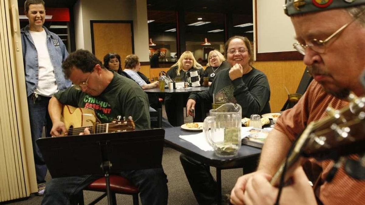 Mike Briggs, left, played guitar in 2009 as his wife Patricia Briggs, center, listened.