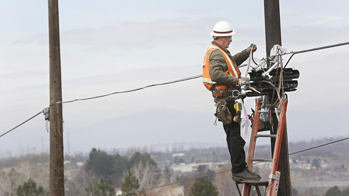 The faint outline of Rattlesnake Mountain is visible through the haze Wednesday as Jim Rosenthal, an employee of Robinson Brothers Construction Inc. of Kennewick, works on communication lines on utility poles along Columbia Park Trail just west of Rockwood Drive in Richland. The contract work, for the site of a new house, is being done for Frontier Communications.