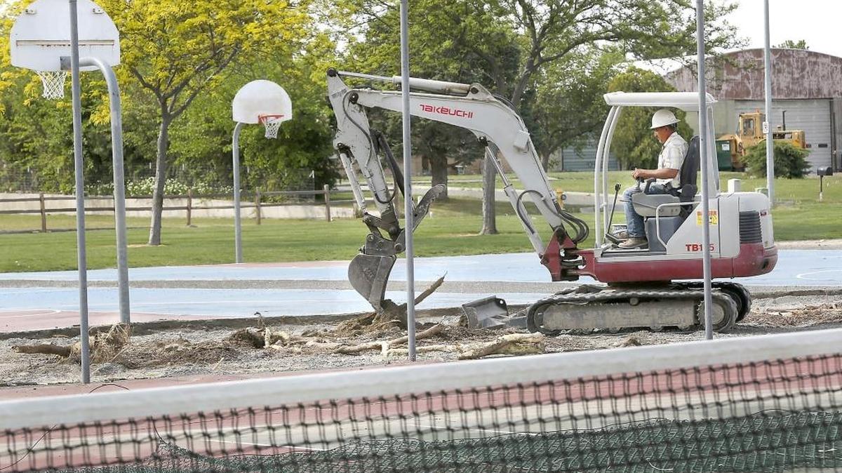 Jose Cisneros of Allstar Construction in Richland works from a small excavator Thursday removing buried tree roots from the previously concrete viewing area between the basketball and tennis courts at Lawrence Scott Park in Kennewick. The work is part of an extensive repair and resurfacing project for the park’s tennis, basketball and pickleball courts. The construction of three new pickleball courts is also part of the city project. The sports courts and area around the work site are closed to the public during construction. The anticipated completion date is June 15.