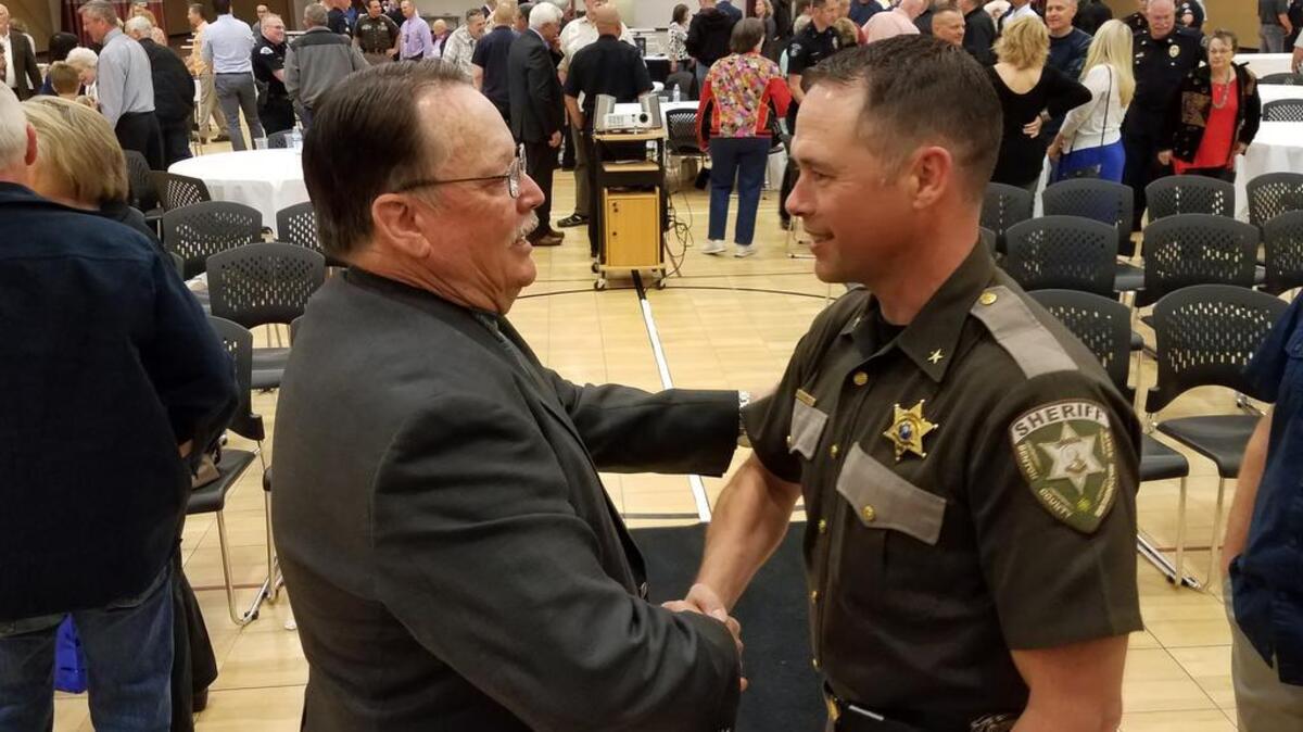 Kennewick police Sgt. Jack Simington, left, shakes hands with Benton County sheriff’s Deputy Jon Law at his retirement party Monday.