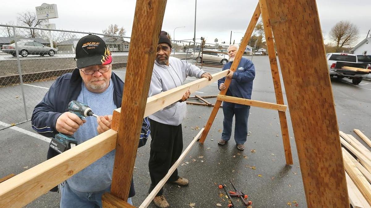 Site director Windle Todd, church member Seymore Finney and Pastor Shane Pooler, from left, work together Monday assembling wooden Christmas tree sales display racks in the parking lot of the Highway Tabernacle Church of God in Kennewick. They were preparing for the arrival of 300 trees being sold as a fundraiser for local community and global children programs sponsored by the church, according to Pooler. They are calling their project: “Buy a Tree, Change a Life.” The church is at the intersection of West Seventh Avenue and Highway 395.