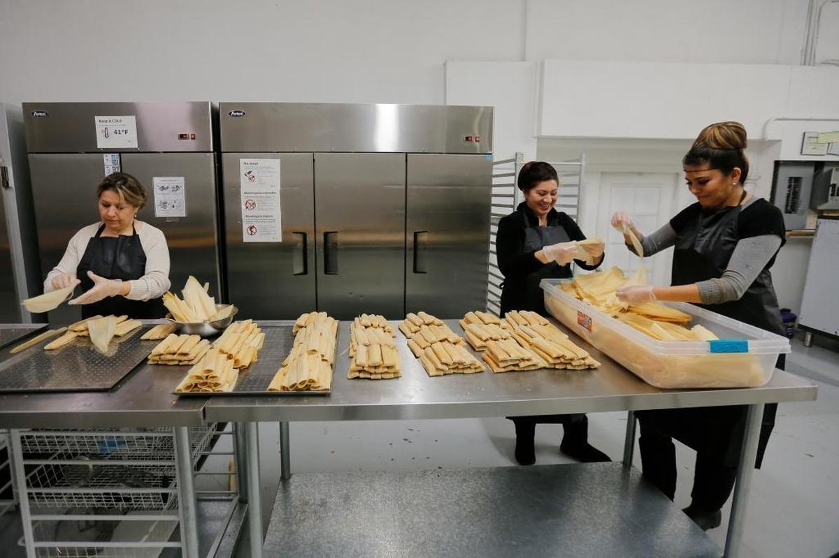 Blanca Idalia Garza, left, and her employees work inside a kitchen in Pasco making tamales.
