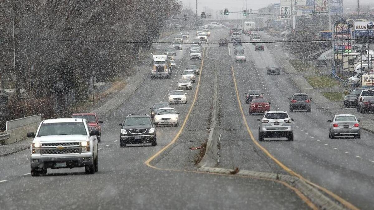 Snowflakes fill the air Friday afternoon as holiday travelers, truckers and local motorists travel through Kennewick on Highway 395.