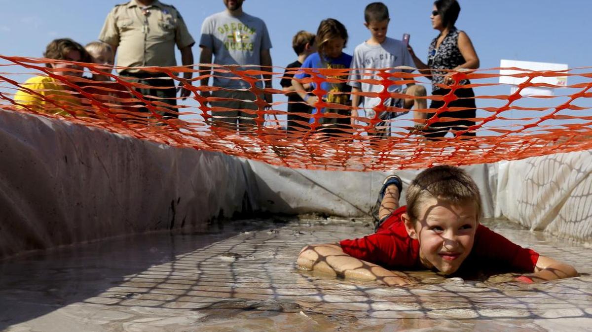 
Friends and family watch Saturday as Gavin Emmerson, 7 of Kennewick, crawls through the mud during the Mud Cubs family challenge course at the Reach museum. The Blue Mountain Council of the Boy Scouts of America organized and ran the first ever obstacle course as a fundraiser.
