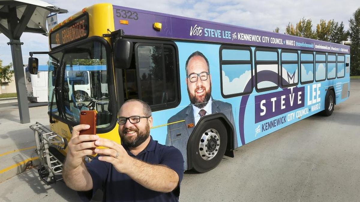 Steve Lee, a Kennewick City Council candidate, snaps a selfie in front of the Ben Franklin Transit bus with his political ad. Lee is raising eyebrows with his plan to spend $85,000 in mostly his own money during his campaign. He is challenging incumbent Greg Jones for Position 2.