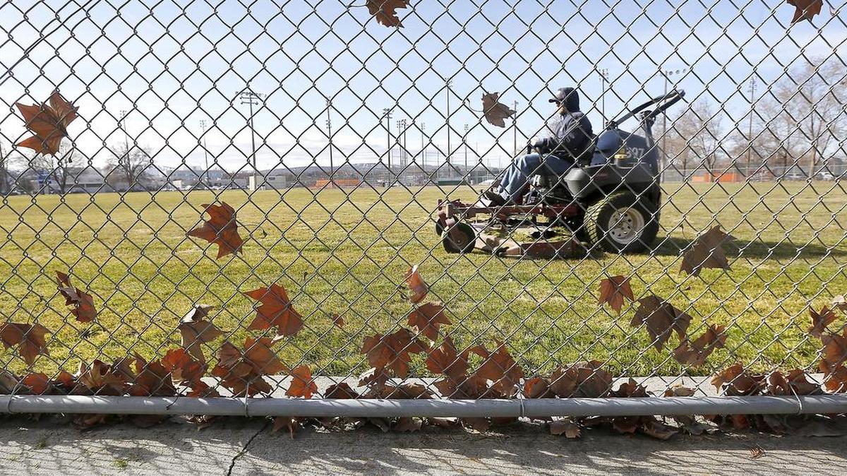 Gusty conditions Wednesday pin blowing leaves against the outfield chain link fencing at the softball fields in downtown Kennewick as a city employee mows the grass in preparation for upcoming use of the fields. The National Weather Service is predicting mostly cloudy skies to return Thursday with a slight chance of rain.