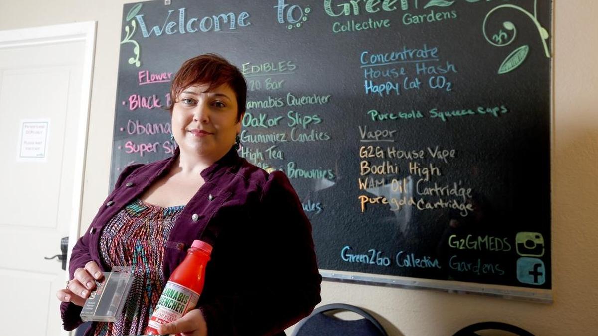 
Jennifer Goulet, an employee at Green2Go Collective Gardens, a medical marijuana dispensary, holds some of the products Monday at the store on State Route 397 in Finley. 
