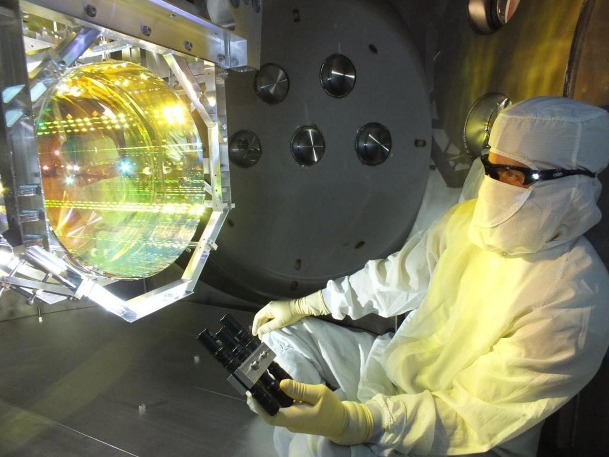A LIGO optics technician inspects one of LIGO’s mirrors by illuminating its surface with light at a glancing angle. It is critcal to LIGO’s operation that mirrors have no contamination.