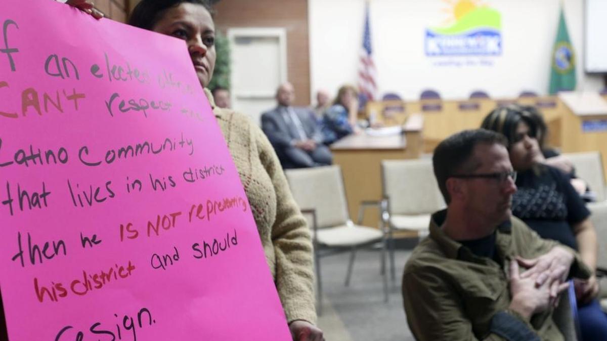 Dora Morfin, a Pasco resident who works in Kennewick, holds a sign Tuesday during the first Kennewick City Council meeting since Councilman Bob Park’s controversial private Facebook post that disparaged Latinos and Pasco. The sign says, “If an elected official can’t respect the Latino community that lives in his district than he is not representing his district and should resign. Thank you.”