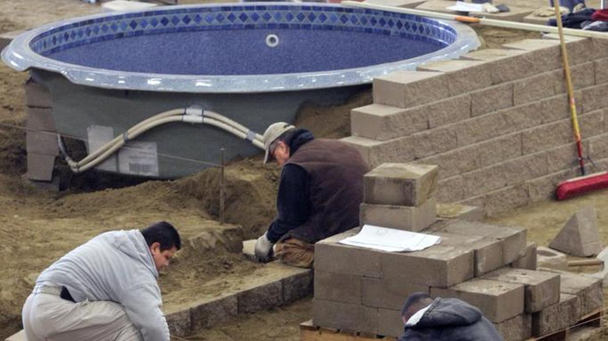 Employees of Premier Landscaping & Design of Richland work on setting up an exhibit featuring a hot tub, wet bar and fire pit at TRAC in Pasco during the Regional Home & Garden Show.