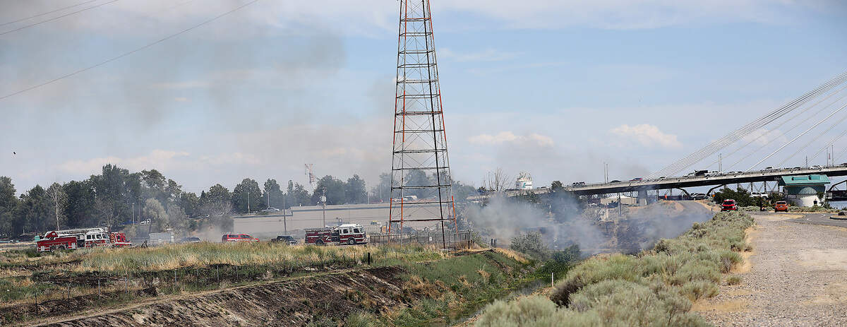 Fire units extinguish a brush fire on the Pasco shoreline that was caused after a floatplane clipped and broke a power line that crossed the Columbia River to Clover Island on Wednesday afternoon and crashed into the water killing two men on board.