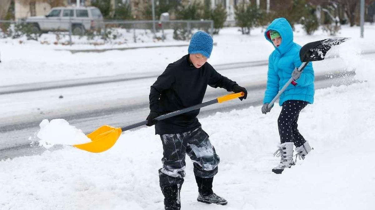 Gavin Smith, 12, and his sister, Madi, 10, work together Thursday morning shoveling snow off the sidewalk in front of their home on West Fourth Avenue in Kennewick.