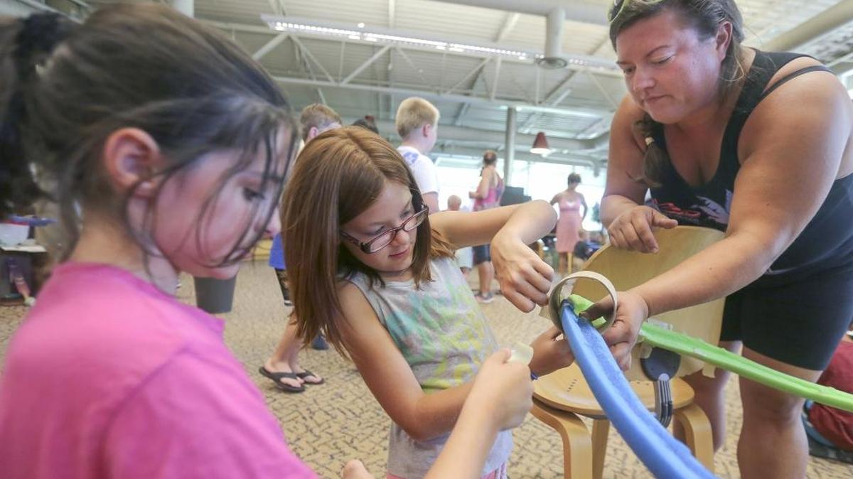 Abigail Questale, 9, left, hands tape to Leina Bean, 8, center, as she and her aunt, Alysha Leyva, help build a maze at the Kennewick Mid-Columbia Library branch on Thursday during Marble Run Madness. It’s an activity for 5-12 year olds for the summer reading challenge. The kids work together in teams and create a maze that the marble will roll through. Watch a video at tricityherald.com/video