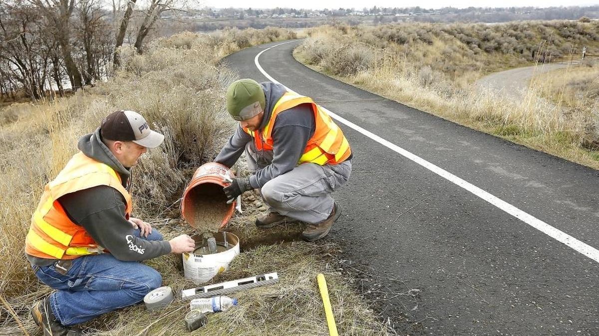 John Hendrickson, left, and Todd Breckel, with the state Department of Transportation, pour the base for a bicycle and pedestrian counter along the Sacagawea Heritage Trail near Road 52. The battery-powered counter will collect information for the state and the city of Pasco on how the trail is used. Similar counters have been installed statewide. The details can be seen online at bit.ly/bikepedpath.