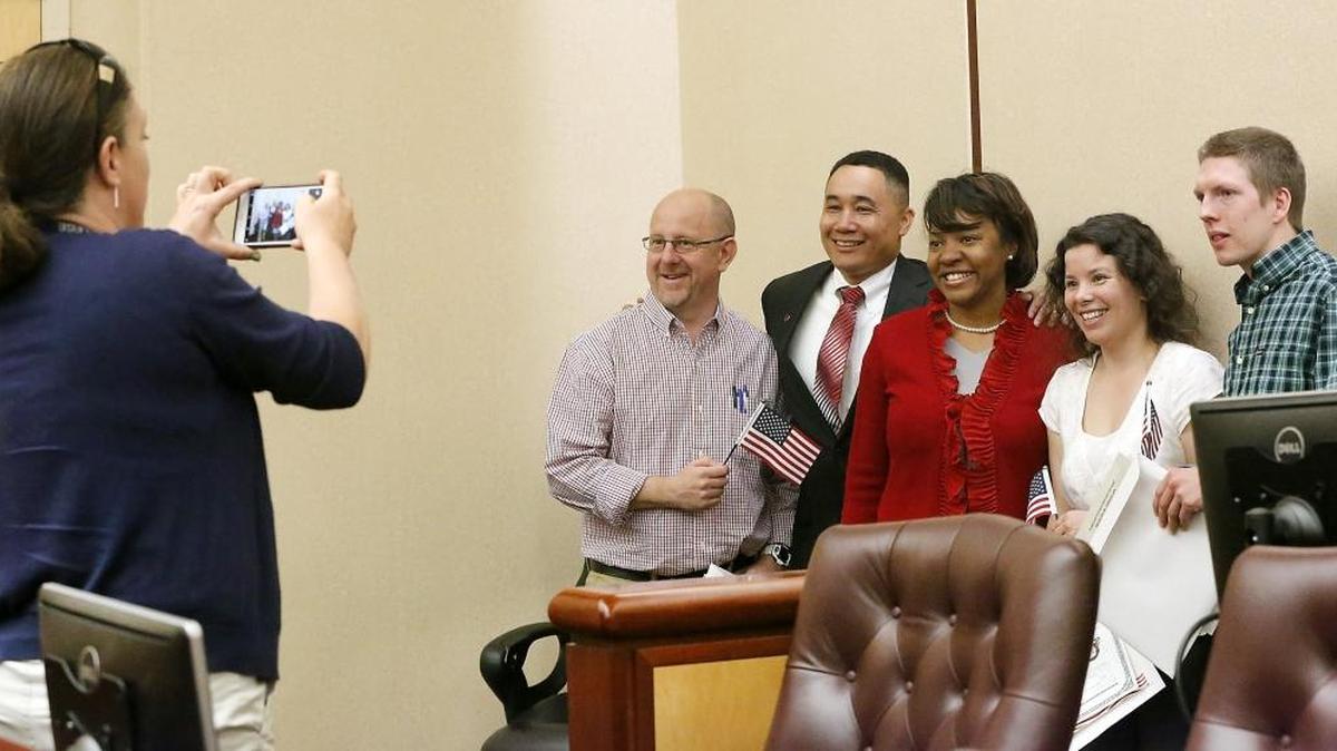 WSU-Tri-Cities Chancellor Keith Moo-Young and his wife, Monika, join a family photo with Andrew Whitford, left, his wife, Maria, and their son, Connor Bardelang, following Monday’s naturalization ceremony at U.S. District Court in Richland. The family from Britain were among 25 local immigrants to become new U.S. citizens. Watch a video at: www.tricityherald.com/video.