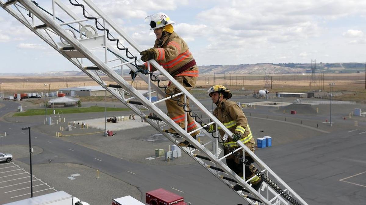 State Rep. Luanne Van Werven, with the 42nd District, is spotted Friday by Richie Dowdy with the Bellingham Fire Department as she climbs an aerial ladder during Fire Ops 101 at the HAMMER training center in Richland. She was one of about 20 civilians and elected officials who went through the training to get a feel for what firefighting is like during the 11th annual event. See a video at www.tricityherald.com.